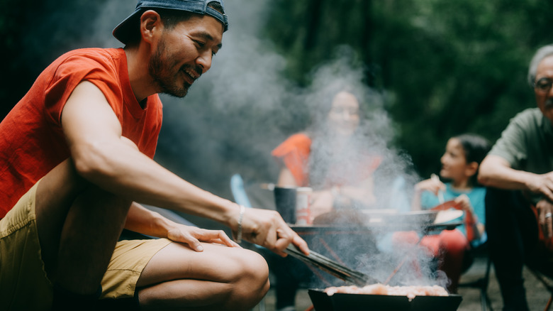 Man grilling over campfire