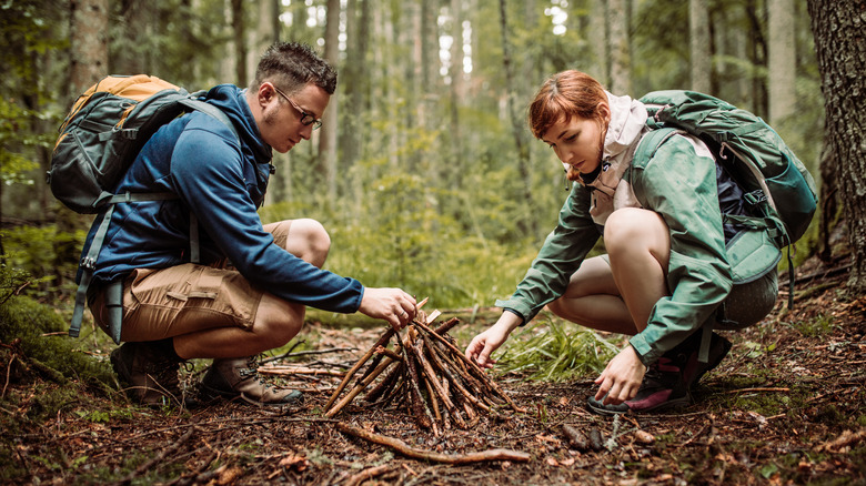 A man and woman building a campfire