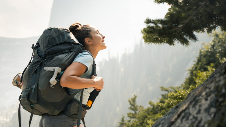 Woman hiking uphill, carrying bear spray