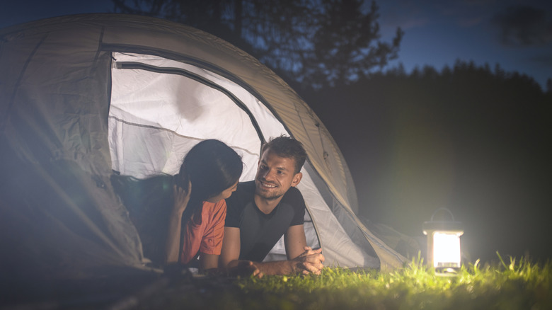 Couple talking outside to tent with lamp