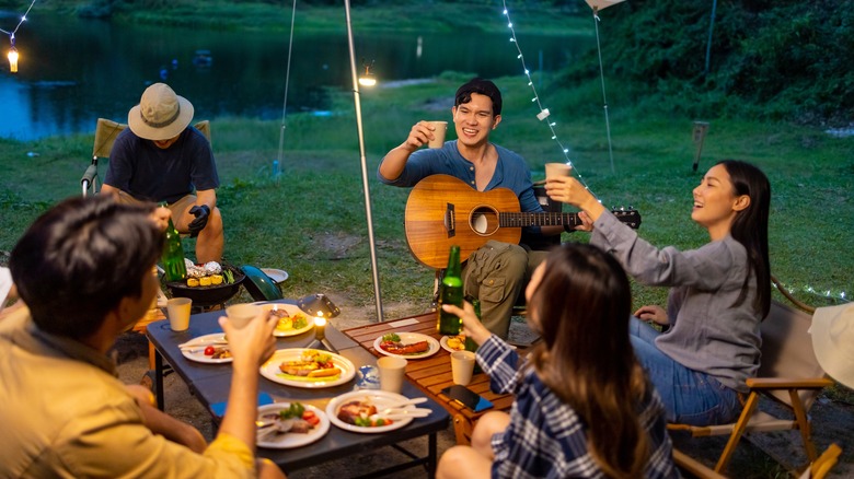 Friends enjoying food and drink while camping