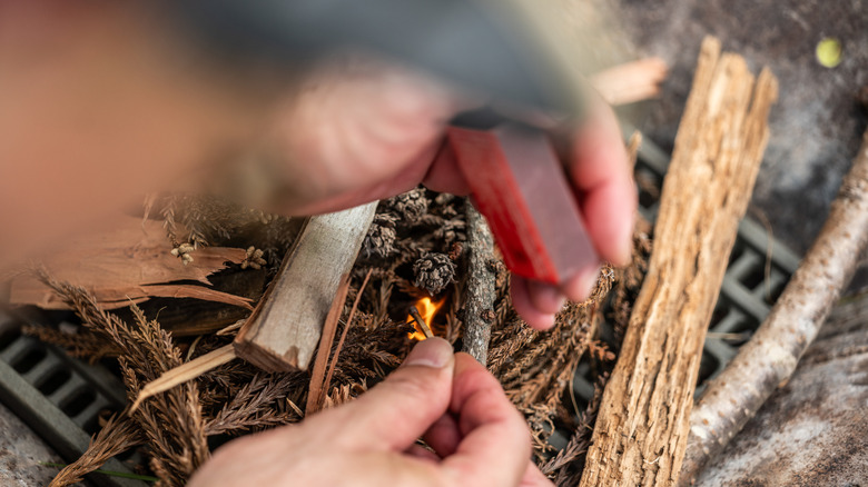 Person lighting a fire from cedarwood sticks