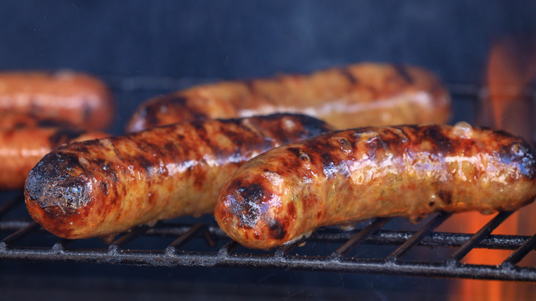 Bratwurst cooking on charcoal grill.