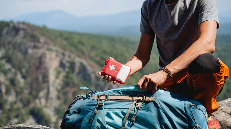 Man putting first aid kit in backpack