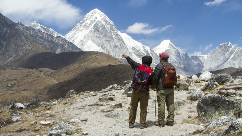 Sherpa pointing at Mount Everest next to hiker