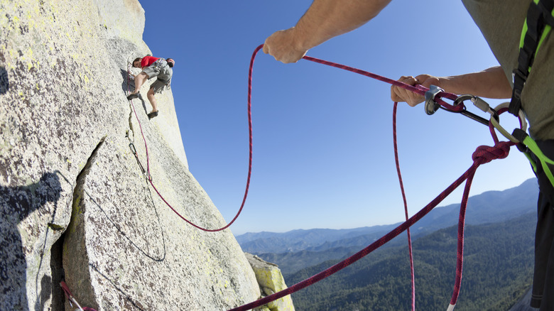 Hand on rope, supporting an un-helmeted climber 