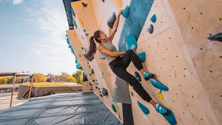 Woman free-climbing slanted rock wall 
