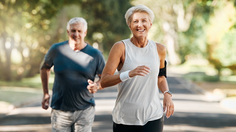 Smiling elderly couple running outdoors