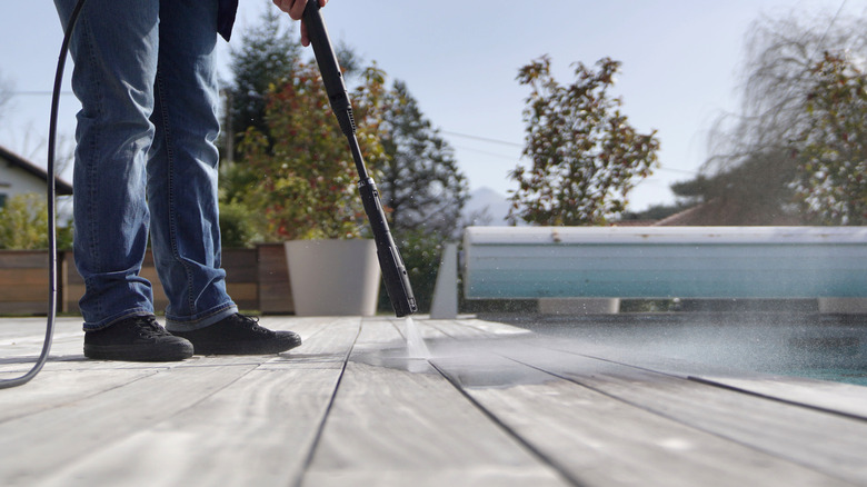 man pressure washing a deck