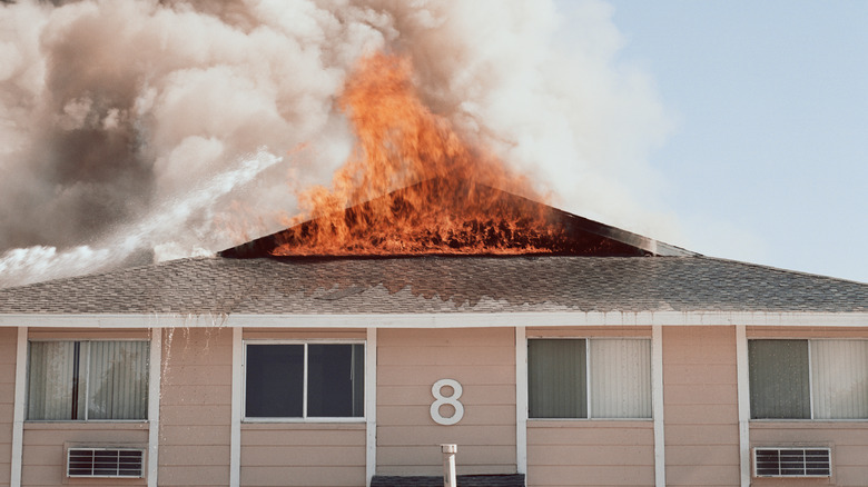 A house with a fire coming out of the attic