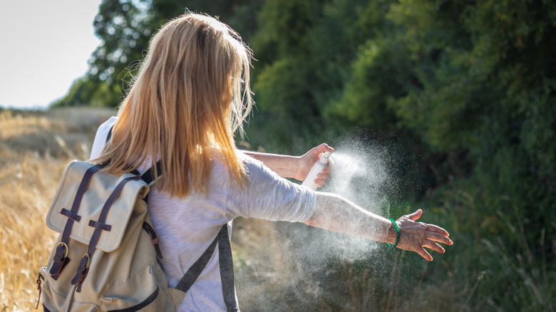 Woman spraying insect repellent on skin