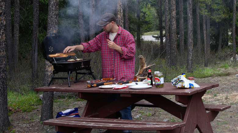 Man grilling on picnic table near RV