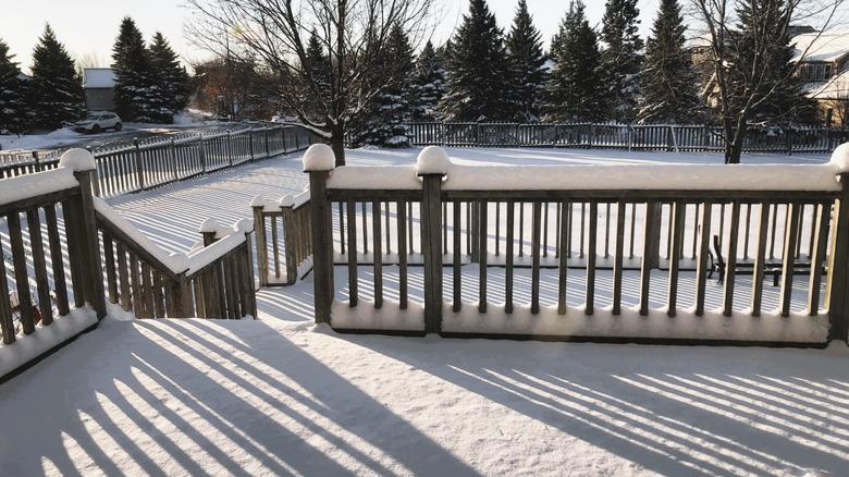 A snow-covered deck with snow piled on top of railings