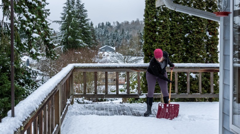 A woman shoveling her wood deck parallel to the boards