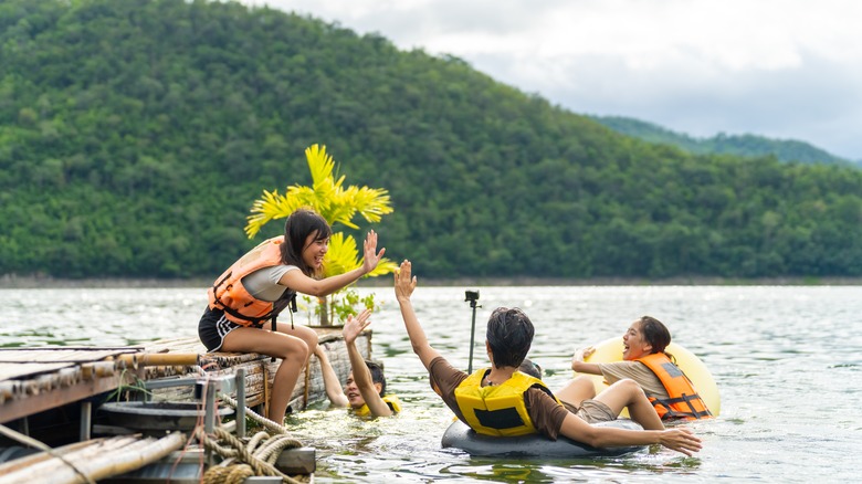 Friends swimming in lake with life vests on