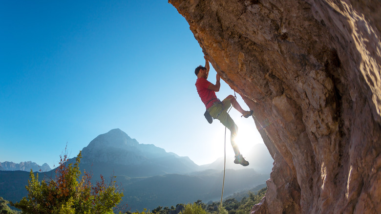 Man climbing up rock with rope