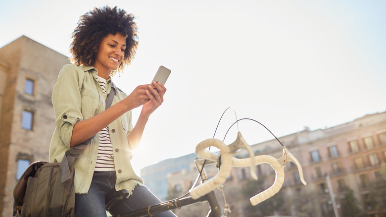 Woman sitting on bike, looking at phone