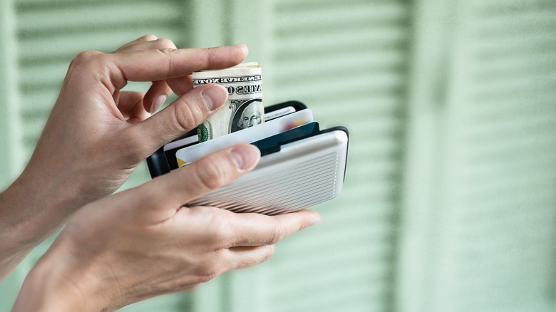 Person putting money in wallet with RFID protection