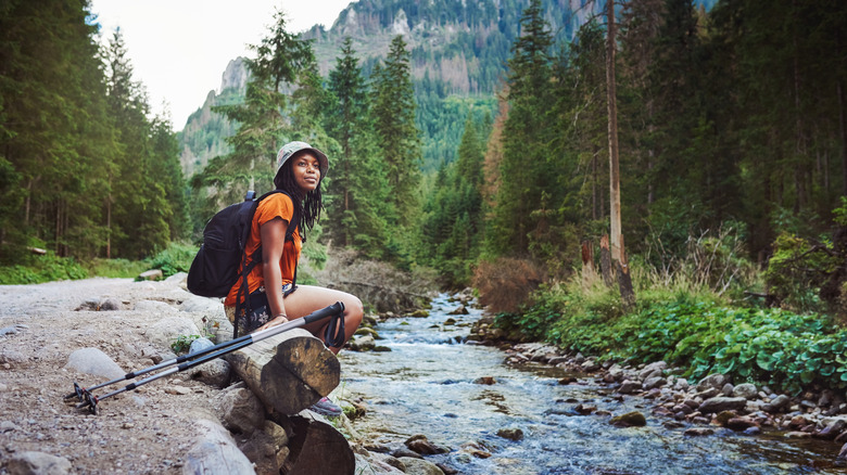 woman sitting by stream on hike