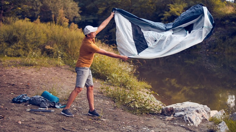 Man shaking dirt from tent