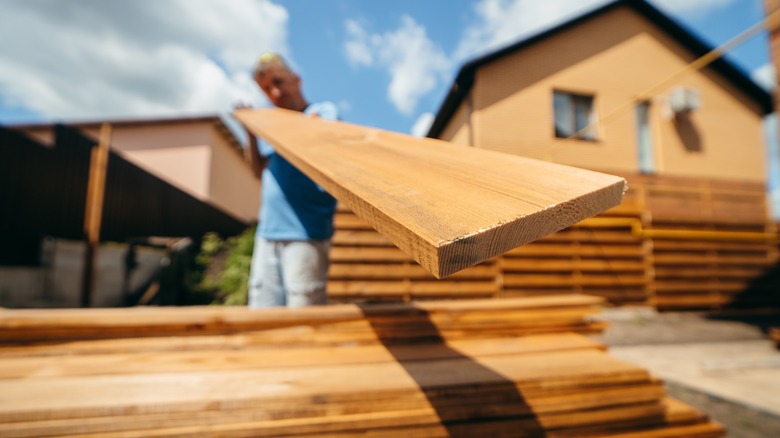 Man grabbing wooden plank from pile