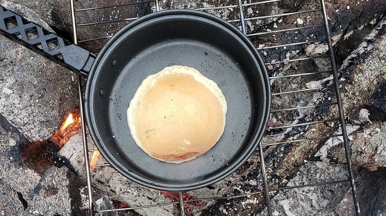 Pancake on a pan over a campfire