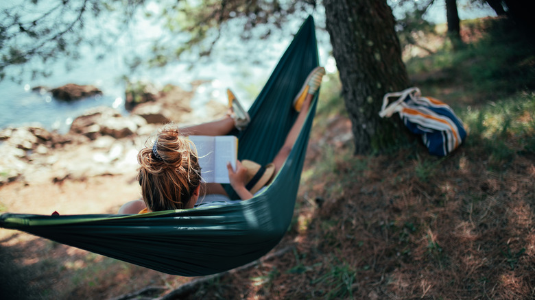 Woman laying on hammock in woods by beach