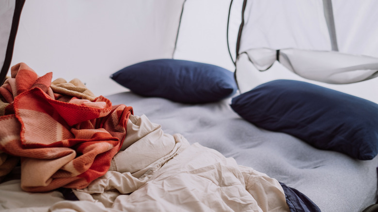 The inside of a tent with an air mattress, sleeping bag, blankets, and pillows set up