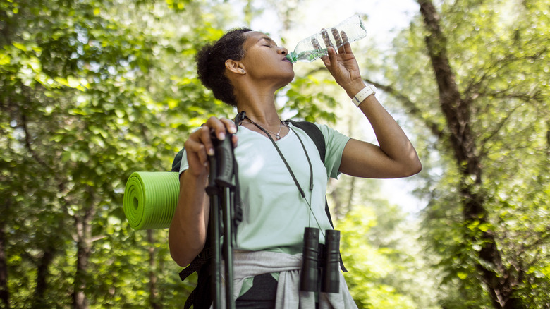 Hiker in forest drinking water