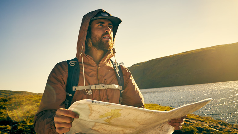 Hiker looking perplexed holding map