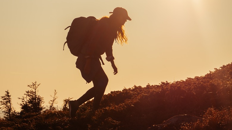 Woman hiking hunched with heavy backpack