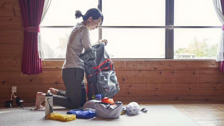 Woman packing hiking gear into backpack