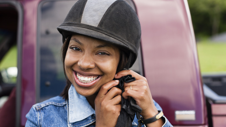 A person buckling a horseback riding helmet