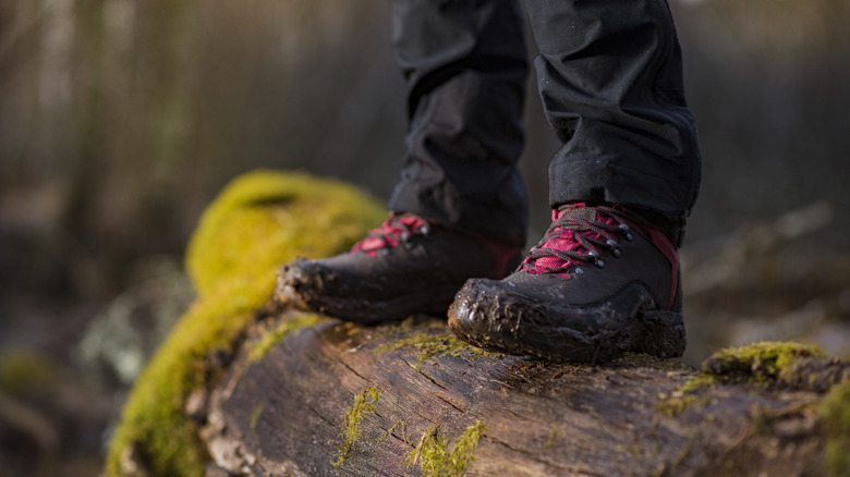 Hiker wearing red and black muddy hiking shoes