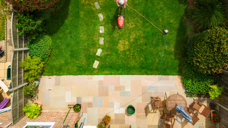 Green grass with patio and man with lawnmower