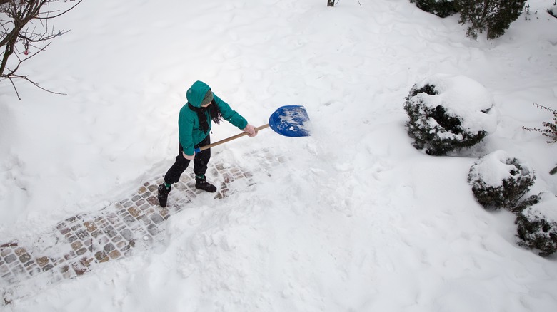 Woman in blue shoveling snow
