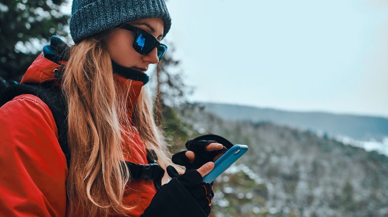 Woman using phone in snowy mountains
