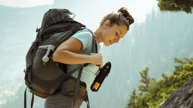 Hiker climbing uphill, carrying bear spray in holster