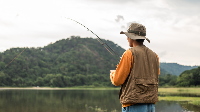 Man fishing, view from behind overlooking lake