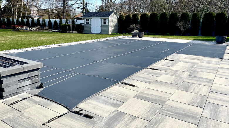 An in-ground pool covered up and secured for the winter