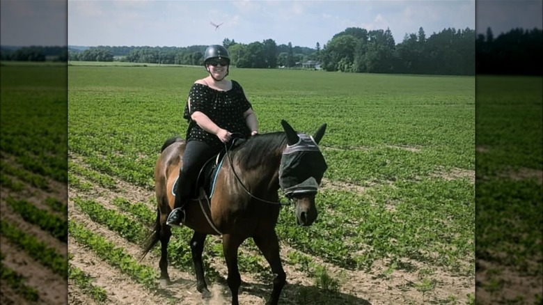 Lady riding a horse with a clip-on dragonfly