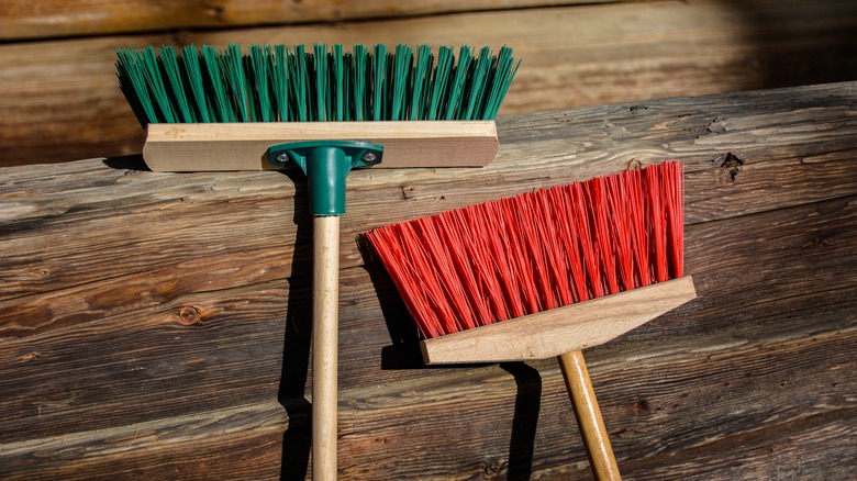 Two different brooms on a wood background