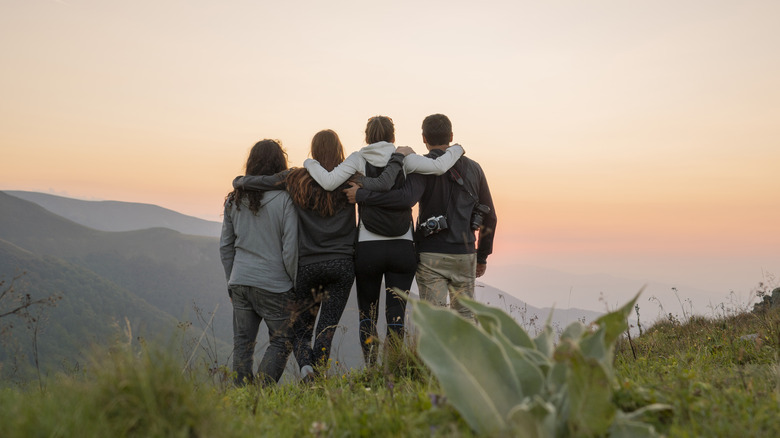 Group of hikers hugging, overlooking cliff