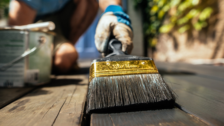 Person preparing a wooden deck