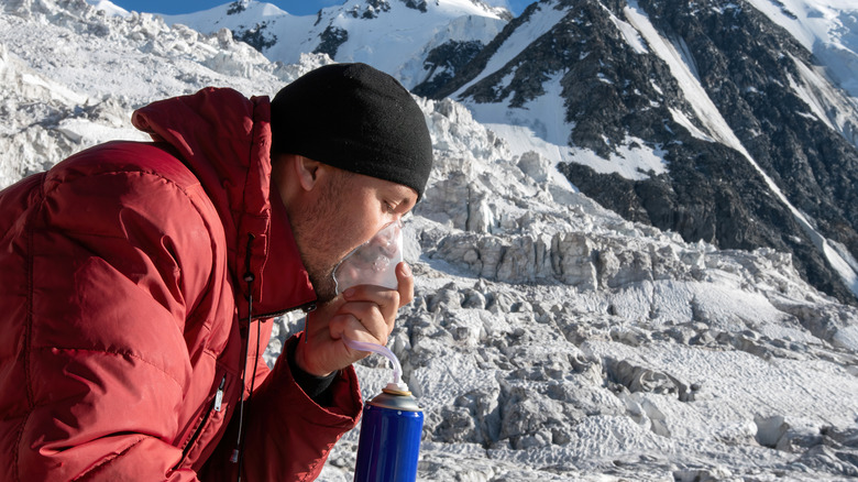 Man using oxygen while seated on snowy mountain