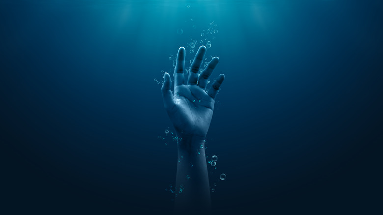 Hand underwater reaching upwards