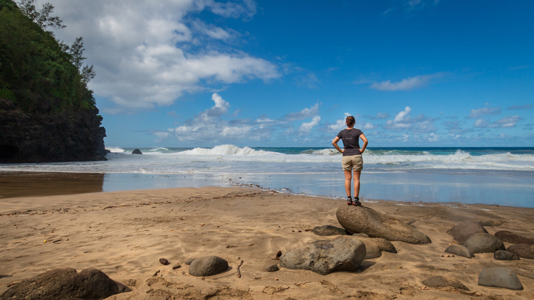 Woman standing on rock and watching the waves at Hanakapiai beach