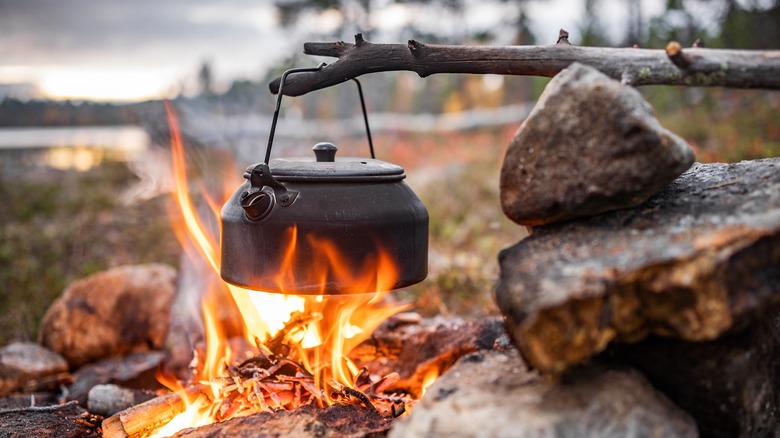 Kettle of coffee over the flames of a campfire