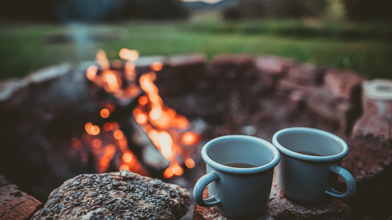 Two blue mugs of coffee by the campfire