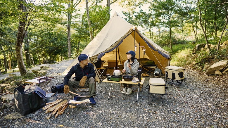 Man and woman prepare bonfire outside of tent